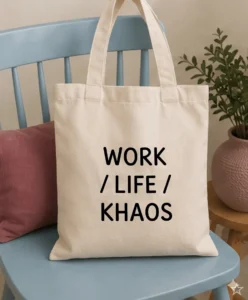 Bolsa de tela color crema sobre una silla azul, con el texto "WORK / LIFE / KHAOS" impreso en letras negras.